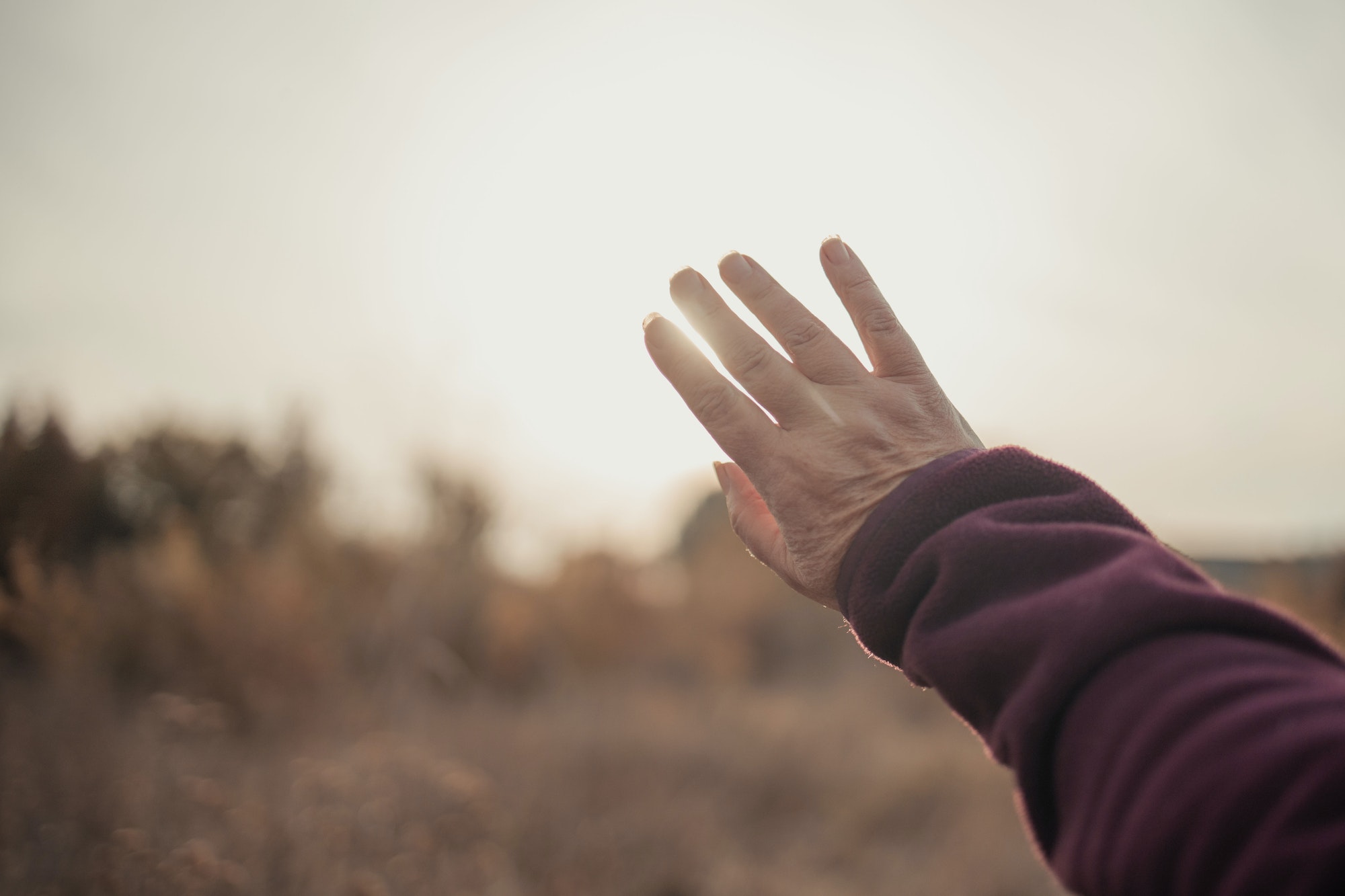 Power of Forgiveness: Female hand reaches for bright sunlight during sunset